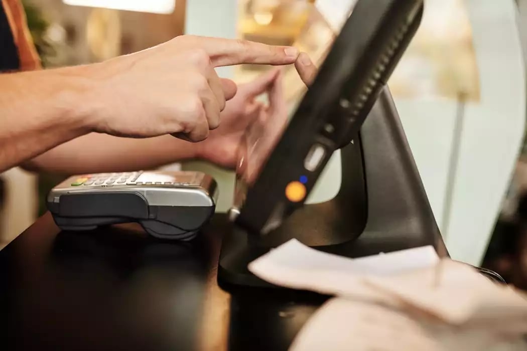 A close-up photo of a server entering items on a restaurant ordering system.