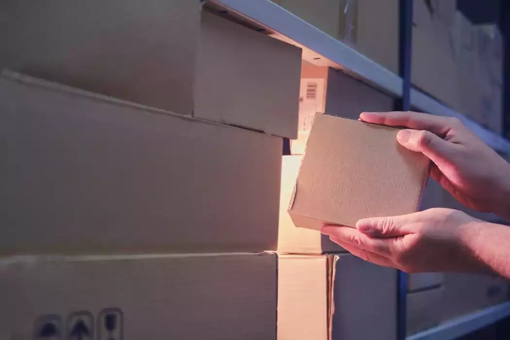 Mid-employee theft; male hands remove a box of non-perishables from a stockroom.